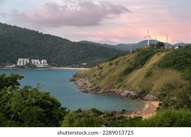 Panoramic view from Windmill sunset viewpoint in Phuket island in Thailand. Purple skies above the azure sea bay and tropical sandy beach. A lonely windmill is on the top of the hill.
