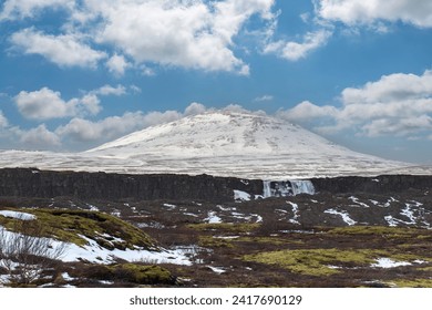 Panoramic view of winter landscape in Thingvellir National Park, Iceland between Eurasian and North American tectonic plates with Öxarárfoss waterfall and snow topped mountains in background