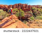 Panoramic view of woman at Kings Canyon Rim Walk with footbridge over Garden of Eden, Watarrka National Park, Australia. Female visitor enjoying scenic views in outback Red Center, Northern Territory.