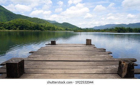 Panoramic view of Wooden bridge lake with Green mountain, bright blue sky and lake at the background with Empty wooden floor. can be used for display product Mock Up. Panoramic Nature Scene.