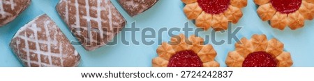 Panoramic web banner featuring glazed gingerbread and flower shaped jam cookies on blue background. Sweet bakery dessert flat lay concept for advertising. Photo