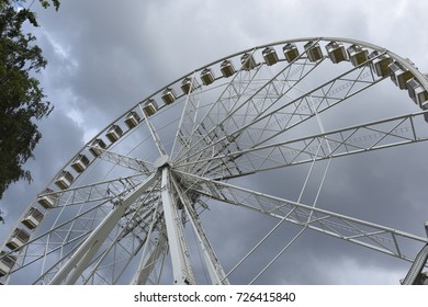 Panoramic wheel under cloudy sky. Ferris wheel under grey sky. Part of spinning wheel.