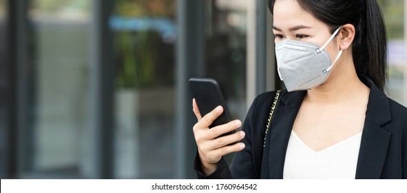 Panoramic Of Young Happy Asian Businesswoman Worker Wear N95 Facemask Smile And Look At Mobile Phone In Concept Back To Work After Covid Crisis, Go To Work Outside Or Outdoor, Work Anywhere Concept.