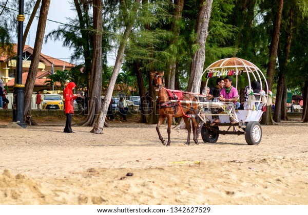 Pantai Puteri, Melaka, Malaysia - December 23\
2018: Happy family riding a horse cart at Pantai Puteri, Melaka. A\
Famous tourism attraction in melaka.\
