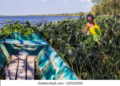 Pantanal, Paraguay in August 2015: An indigenous girl sitting next to a small fishermen's boat in Puerto Pollo at Rio Paraguay in Paraguay's Pantanal
