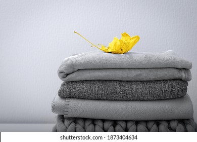 Pantone colors 2021    Illuminating Yellow   Ultimate Gray  Crop stack gray woolen knitted blankets  warm plaids decorated maple leaf  autumn cozy concept