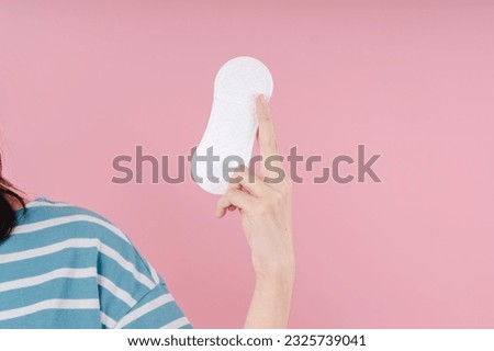 Panty liner in female hand on a pink background. Menstruation, critical days, feminine hygiene