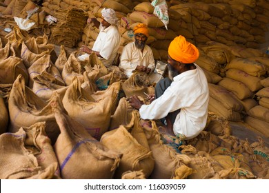 Paonta Sahib, India - May 23, 2009: Sikh Men Packing Burlap Sacks Full Of Charity Grain In Part Of Their Philanthropic Religious Duties To Help The Needy