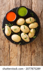 Papas arrugadas wrinkly potatoes is a traditional boiled potato dish served with a mojo rojo and mojo verde sauces close up in the plate on the table. Vertical top view from above - Shutterstock ID 2077875289