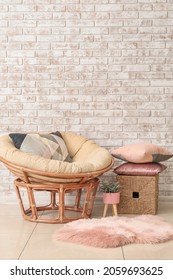 Papasan Chair With Soft Cushions Near Brick Wall In Room