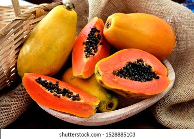The papaya fruits in a wooden pot and a straw basket and rustic fabric at the background