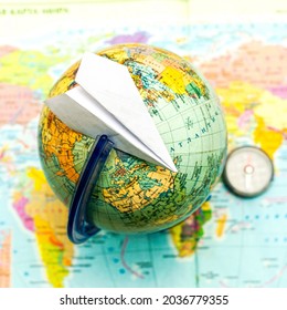 Paper Airplane On A Globe On The Background Of A World Map Travel Tourism Concept. High Quality Photo