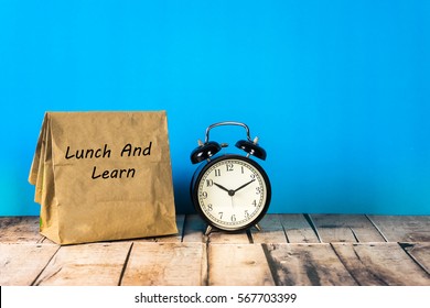 Paper Bag And Clock On Blue Background With A Notes Lunch And Learn.