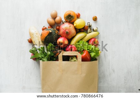 Paper bag of different health food on white wooden background. Top view. Flat lay