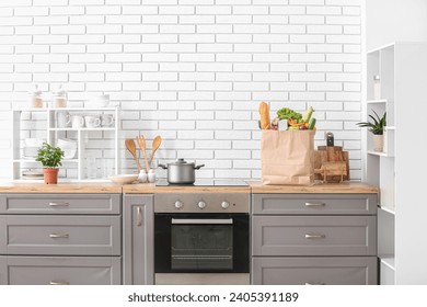 Paper bag with different products and utensils on counter in kitchen - Powered by Shutterstock