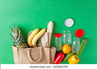 Paper Bag With Fresh Pineapple, Bread Loaf, Bananas, Cucumber, Red And Yellow Peppers, Empty Glass Jars On Green Background For Free Plastic Shopping, Zero Waste Concept