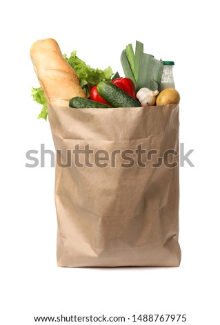 Paper bag with fresh vegetables and bread on white background