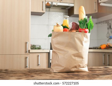 Paper bag full of healthy food on a wooden table in the kitchen close up with copy space