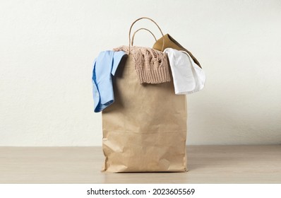 Paper bag full of used clothes for recycling on the desk against white wall.Empty space