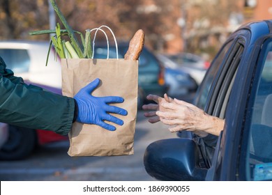 paper bag with groceries handed to needy elderly person in vehicle - Shutterstock ID 1869390055