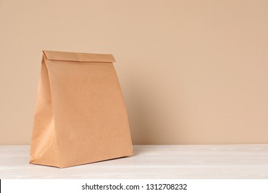 Paper Bag On Table Against Color Background. Mockup For Design