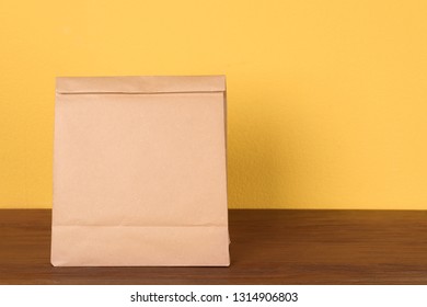 Paper Bag On Table Against Color Background. Mockup For Design