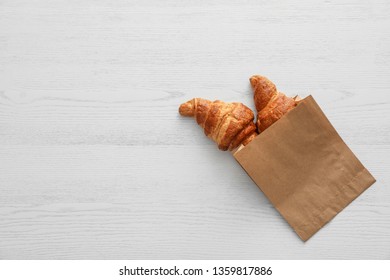 Paper Bag With Pastry On Light Wooden Background, Top View With Space For Text