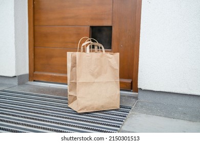 Paper bag with products left by courier of food delivery service during corona virus spreading at front door home - Powered by Shutterstock