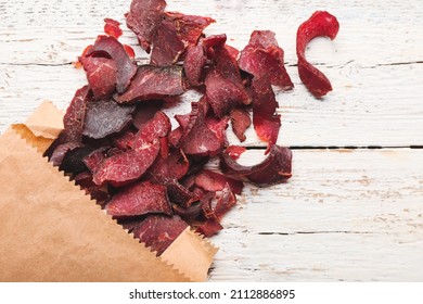 Paper Bag With Spicy Beef Jerky On White Wooden Background