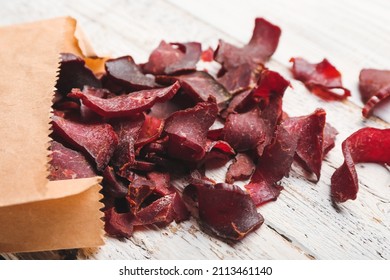 Paper Bag With Spicy Beef Jerky On White Wooden Background