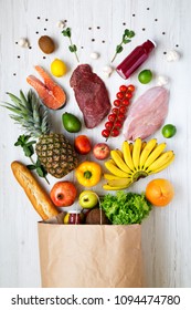 Paper Bag Of Various Healthy Products On White Wooden Background, From Above. Health Food. Flat Lay. Top View.