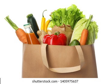 Paper bag with vegetables and bottle of juice on white background, closeup