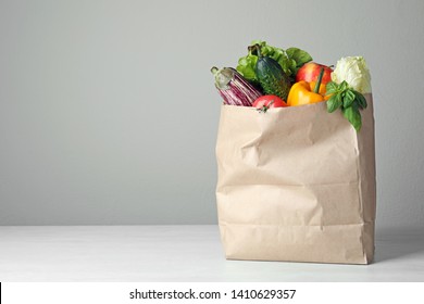 Paper bag with vegetables on table against grey background. Space for text
