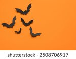 Paper bats for Halloween party on orange background