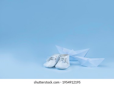 Paper boat and baby booties on light blue background. Greeting card, baby shower invitation, baby birth, gender reveal concept