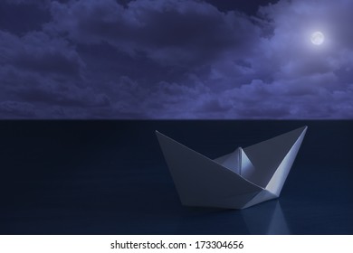 Paper boat floating in the sea at night - Powered by Shutterstock