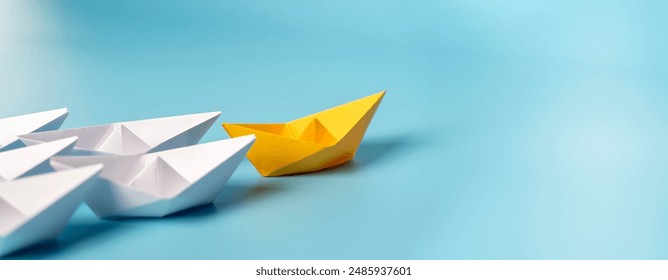 .Paper boat leads the fleet with new ones joining the team. Teamwork, cooperation, leadership, partnership and participation. Leadership concept, yellow leader boat leading boats, on blue background.