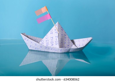 Paper boat made from mathematics notebook paper. Concept of creativity in education. Origami paper ship sailing on blue water surface. - Powered by Shutterstock