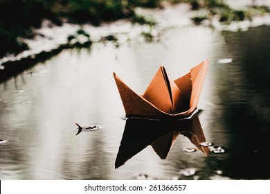Paper boat sailing on quiet water surface.