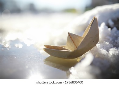 Paper Boat In The Water On The Street. The Concept Early Spring. Melting Snow And An Origami Boat On Water Waves.