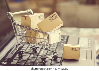 Paper boxes in a shopping cart on a laptop keyboard. Ideas about e-commerce, e-commerce or electronic commerce is a transaction of buying or selling goods or services online over the internet. - Shutterstock ID 577492282