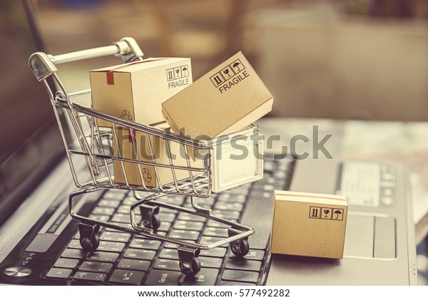 Paper boxes in a shopping cart on a laptop\
keyboard. Ideas about e-commerce, e-commerce or electronic commerce\
is a transaction of buying or selling goods or services online over\
the internet.