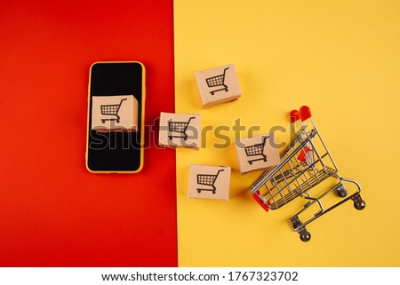 Paper brown boxes on smartphone and trolley isolate on colorful background. The concept of delivery of goods from the online store to the house