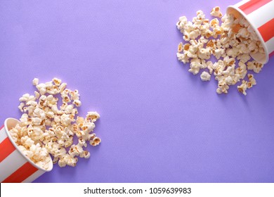 Paper buckets with tasty scattered popcorn on color background - Powered by Shutterstock