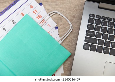 Paper Calendar And Shopping Bag With Laptop On Wooden Table