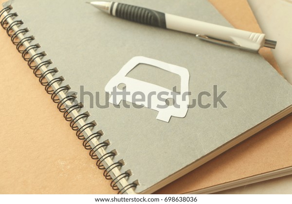 Paper car on notebook with\
pen,