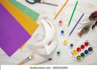 Paper Carnival Mask And Paints DIY On A White Wooden Background. Mardi Gras Concept. Top View