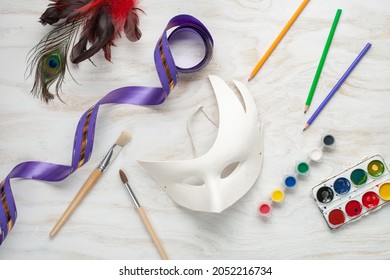 Paper Carnival Mask And Paints DIY On A White Wooden Background. Mardi Gras Concept. Top View