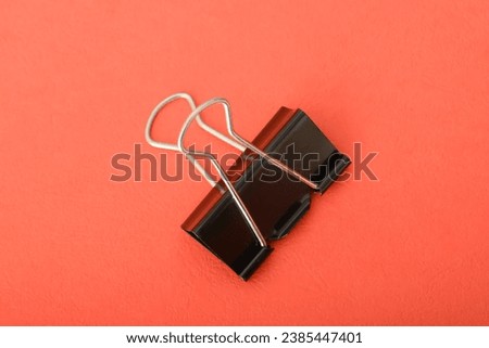Paper clip isolated on a red background. A paper clip is a simple yet ingenious office tool designed to hold papers together