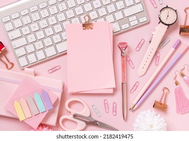 Paper with a clip, Pink school accessories and keyboard on light pink, Top view, mockup. Girly workplace with notebook, scissors, pencil, pen, paperclips, cards and watch. Back to school 